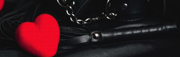 Leather whip and handcuffs for BDSM sex with red hearts as a symbol of Valentine's day