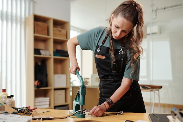 Foto lavoratore di cuoio che utilizza la pressa a mano