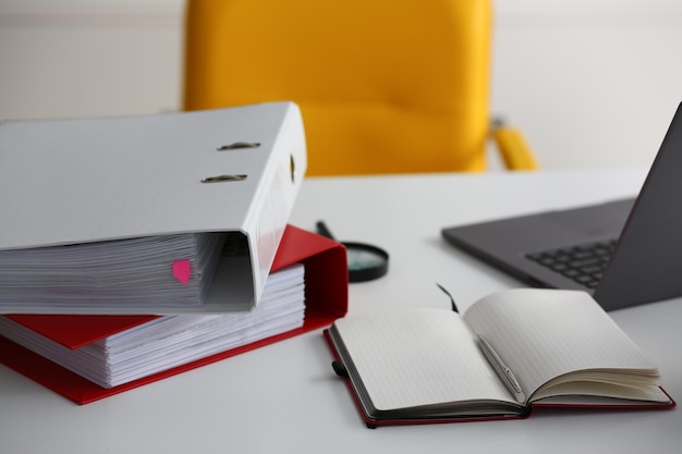 Leather yellow armchair and laptop with folders at workplace in office