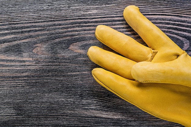 Leather yellow working safety glove on vintage wood board construction concept