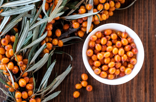 Leaves and berries of orange sea ​​buckthorn on wooden table 