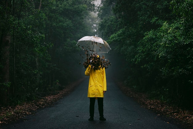 Foto foglie che cadono sull'uomo che tiene l'ombrello