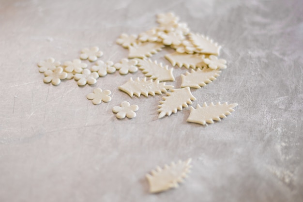 Leaves and flowers of dough. Shaped pieces of raw pastry. Decoration for a pie. Cook food and create art.