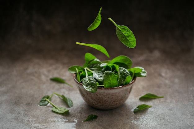 Leaves of fresh baby spinach in a Bowl. Flying leaves. Dark organic green leaves. Healthy vegan food lifestyle concept