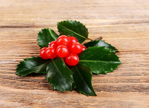 Leaves of mistletoe with berries on wooden surface