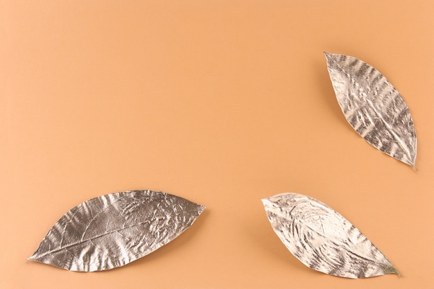 Leaves painted in gold on an orange background. Golden autumn concept.