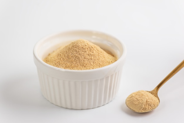 Lecithin powder in a bowl with a spoon on a white