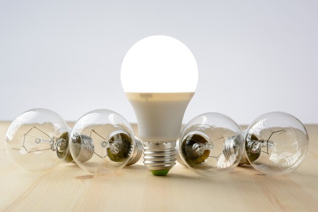 LED lamp standing on a wooden table, near an incandescent lamp lie