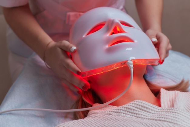 LED light antiaging mask for facial skin care in a spa slow motion A woman lies on a couch in a special mask Modern technologies of beauty and health