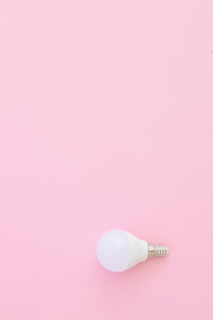 LED light bulb lies on a pastel pink background Energy saving concept Minimalism top view