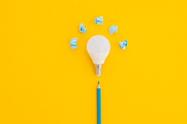 LED light bulb lies on a pastel yellow background Energy saving concept Minimalism top view