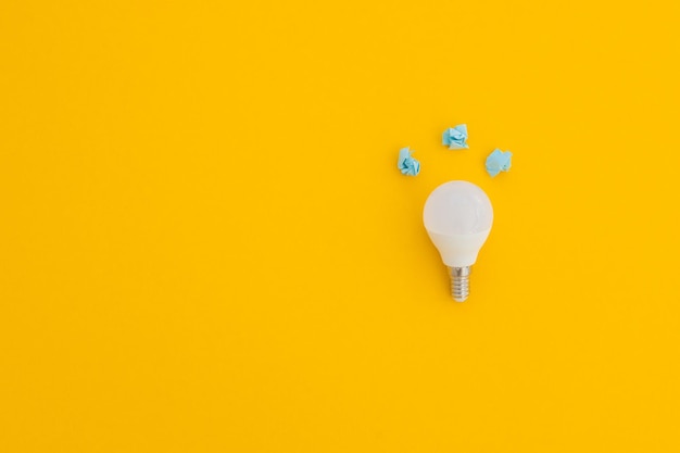 LED light bulb lies on a pastel yellow background Energy saving concept Minimalism top view