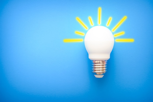 Led light bulb with yellow rays on blue background 