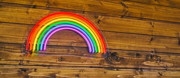 Photo led neon rainbow hanging on the wooden wall