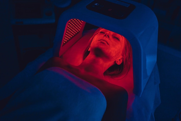 LED red light is treating the facial skin of a young woman