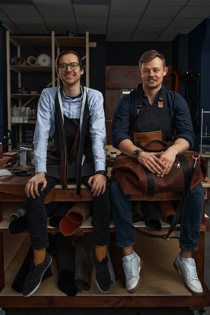 Lederen ambachtslieden werken aan het maken van measupenets in patronen aan tafel in de werkplaatsstudio.