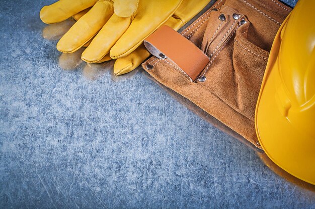 Lederen beschermende handschoenen gereedschapsgordel bouwhelm op metalen achtergrond bouwconcept