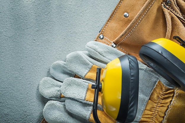 Lederen gereedschapsriem beschermende handschoenen oorbeschermers op betonnen ondergrond