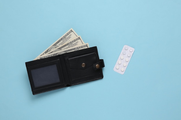 Lederen portemonnee met honderd-dollarbiljetten en blister van pillen op een blauwe achtergrond