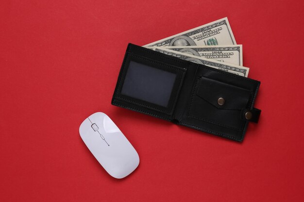Lederen portemonnee met honderd-dollarbiljetten en pc-muis op een rode achtergrond Online betalingen