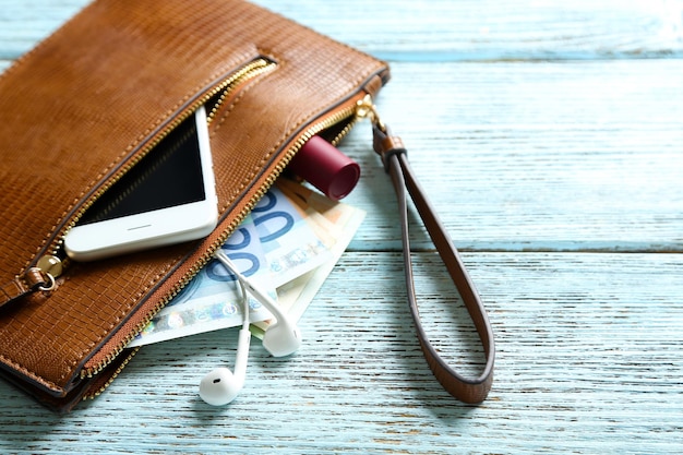 Foto lederen portemonnee met mobiele telefoon en eurobankbiljetten op houten achtergrond