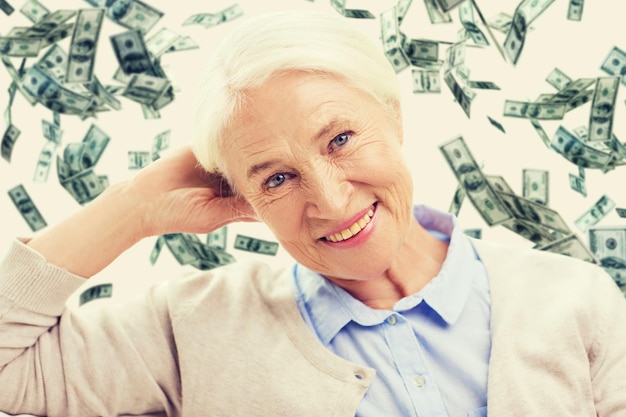 Foto leeftijd, pensioen, financiën, verzekeringen en mensenconcept - gelukkige glimlachende hogere vrouw over de regen van het dollargeld op background