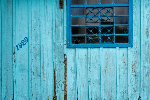 Leeftijd rustieke houten achtergrondstructuur in blauw met ouder venster.
