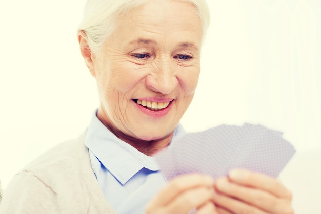 leeftijd, spel, gok, poker en mensen concept - gelukkig lachende senior vrouw speelkaarten thuis