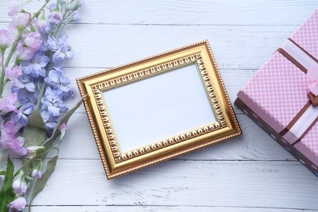 Leeg afbeeldingsframe, geschenkdoos en bloem op tafel.