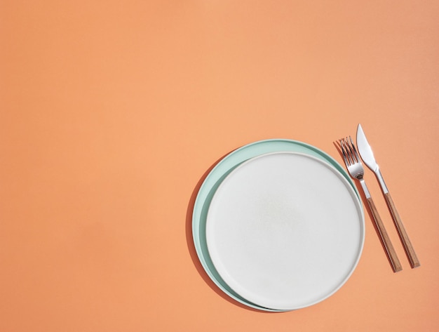 Leeg bord en bestek op oranje achtergrondweergave van bovenaf met kopieerruimte