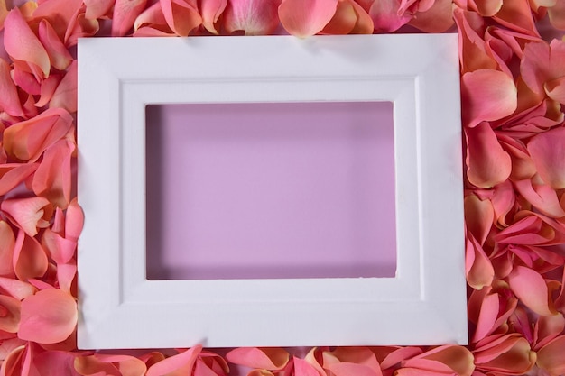 Leeg fotolijst omringd door roze roosblaadjes