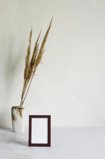 Leeg frame en boeket gedroogde bloemen aartjes in een fles op grijze achtergrond