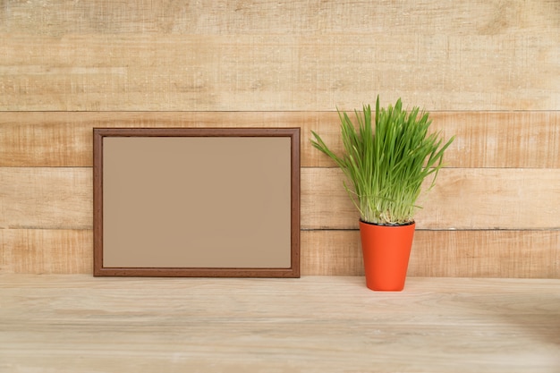 Leeg frame op een houten muur. Groene kamerplant op de tafel. Plaats voor tekst.