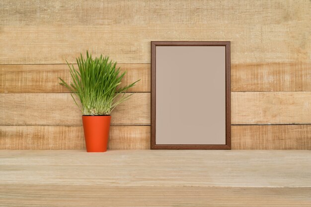 Leeg frame op een houten muur. Groene kamerplant op de tafel.