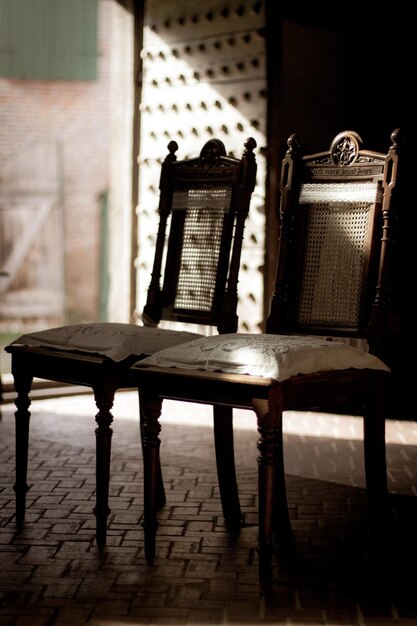 Foto leeg handgemaakte houten stoelen voor de open oude deur met een straal zonneschijn