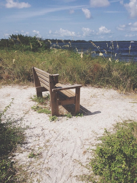 Foto leeg houten bank op het strand tegen de lucht