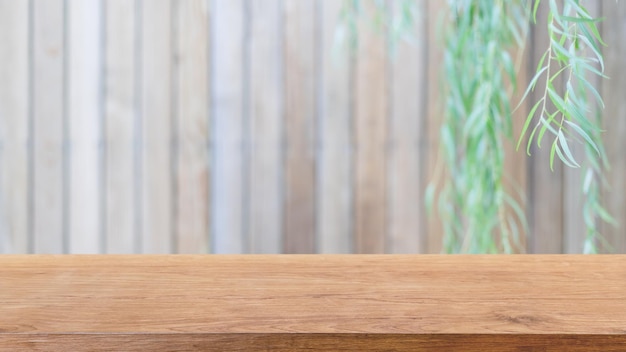 Leeg houten tafelblad en vage houten muur op tuinachtergrond met groene bladeren - kan worden gebruikt voor het weergeven of monteren van uw producten.