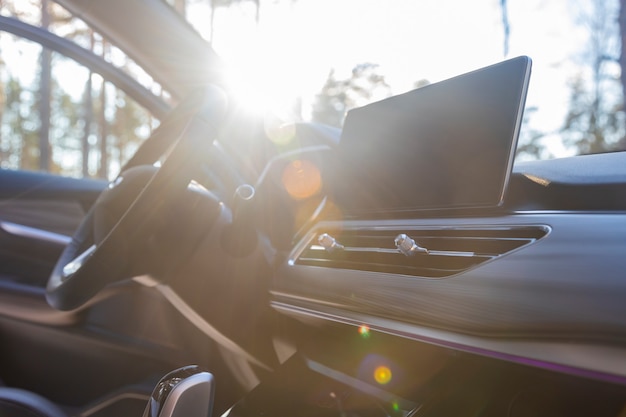 leeg interieur van een premium auto in de zon... multimediamonitor, interieurventilatiedeflectors, stuurwiel. geen mensen.