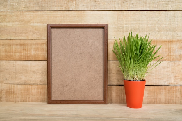 Leeg kader op een houten muur en Groene kamerplant op de lijst