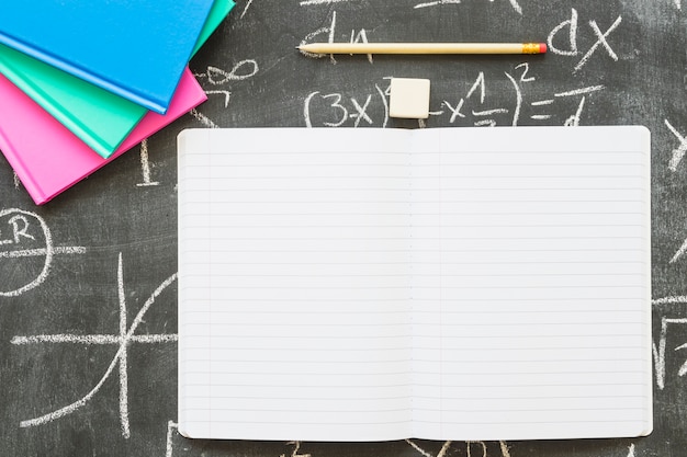 Foto leeg notitieboekje met pen en boeken op schoolbord