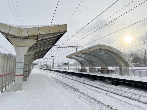 Leeg perron zonder passagiers in de winter bij de zonsondergang. Spoorweg, koud weer concept