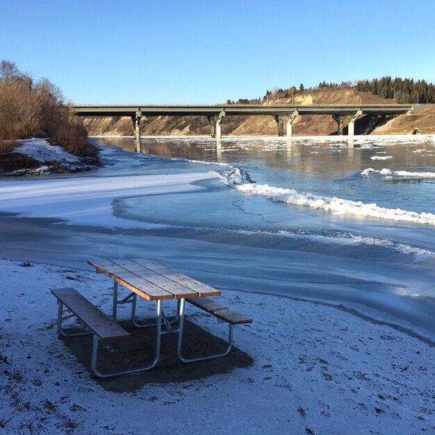 Leeg picknicktafel bij de rivier tijdens de winter tegen een heldere lucht