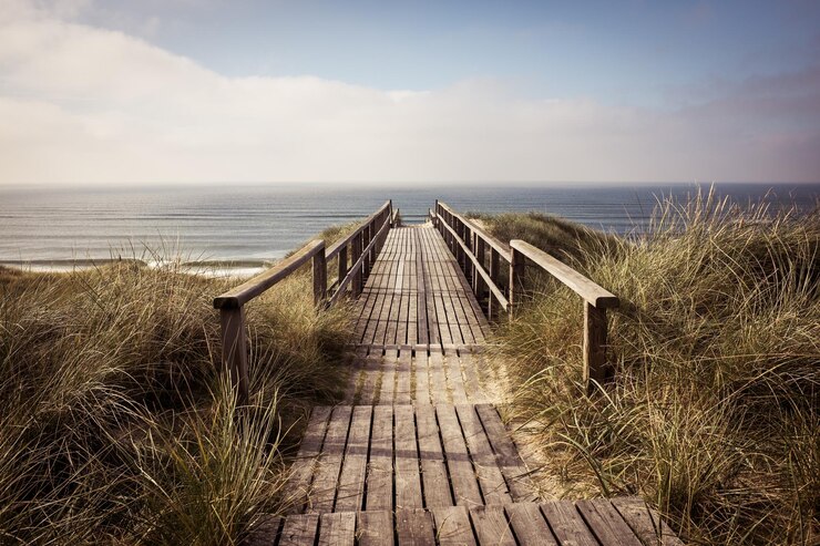 Foto leeg promenade die leidt naar een rustige zee tegen een bewolkte lucht