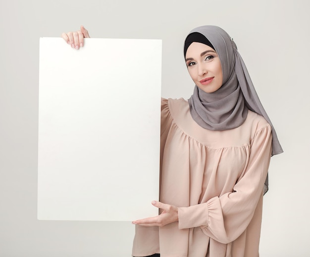 Leeg reclamebord voor Ramadan-groet. Mooie moslimvrouw in hijab met witte poster met kopieerruimte