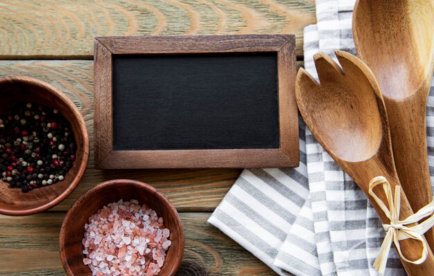 Leeg schoolbord en keukengerei met kruiden op een oude houten tafel