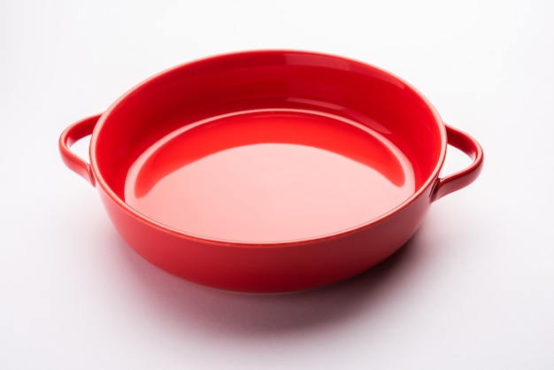 Leeg servies - rode keramische kom of bakvormen zonder voedsel op wit oppervlak