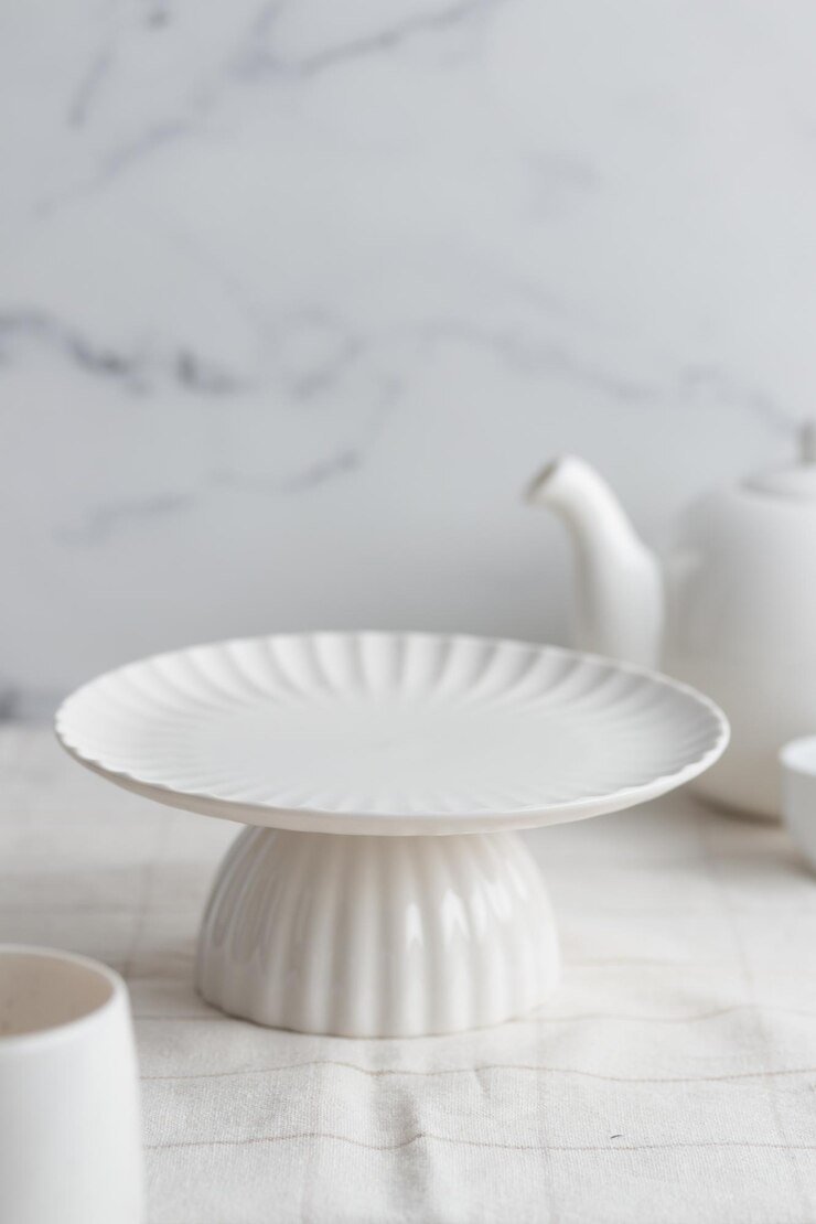 Leeg servies wit cakestandon witte achtergrond voor een dessert verticale foto met een kopie ruimte