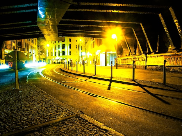 Foto leeg stadsstraat onder brug tegen verlichte gebouwen's nachts