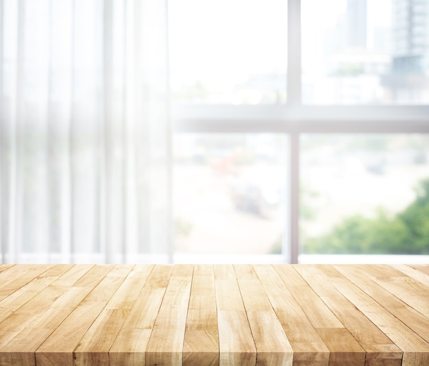Leeg van houten tafelblad op vervaging van wit gordijn met raam uitzicht