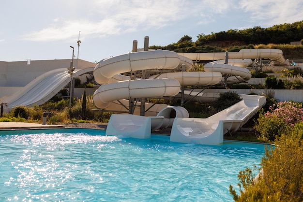 Leeg waterpark met hoge witte glijbanen, zwembaden en witte ligstoelen